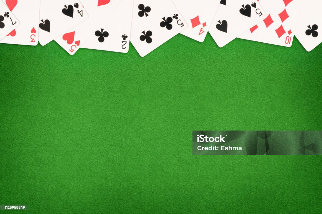 Cards on green felt casino table background Cards on green felt casino table background. Template with copy space in center Playing Card Stock Photo