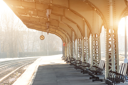 Empty platform with clock at railway station, sunny day