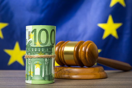 Euro banknotes with a wooden court gavel against European union flag as a concept of corruption in the judicial system