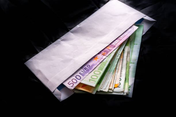 istock Euro banknotes in salary envelope. Open envelope with money banknotes on table. White envelope with Euro bills. Closeup on Envelope full of euro cash. Euro money currency. International monetary 1125967076