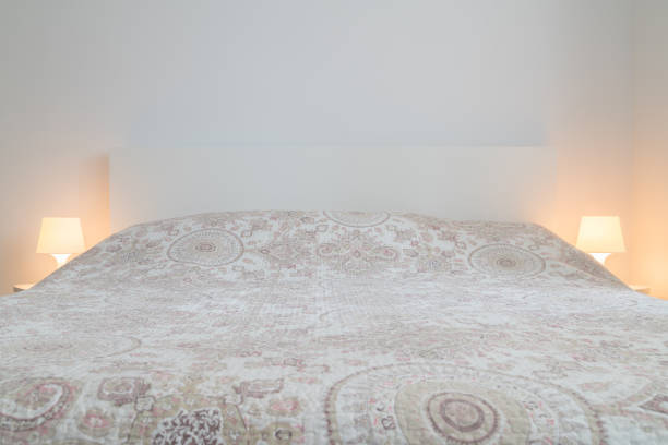 istock Front of the bed with bed sheets and pillows in sleeping room with bed lights on the sides. Comfort, choosing mattress for sleeping 1125967871