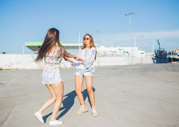Two young women are spinning in circles on a parking lot