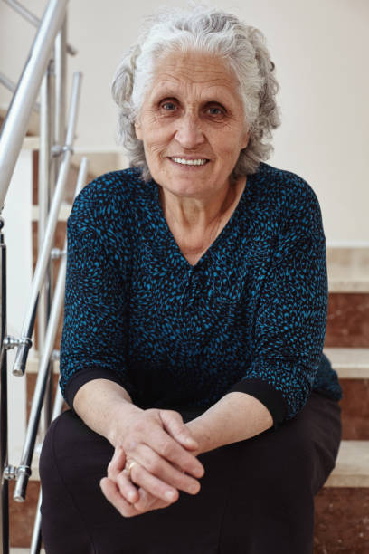 istock Happy old woman sitting on steps and smiling at camera 1125971313