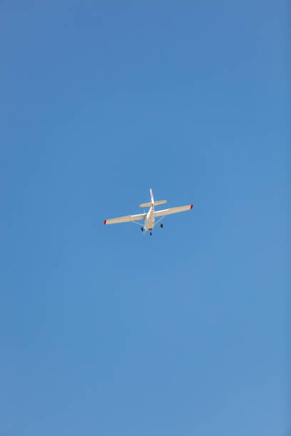 un blanco cessna 172 avión durante vuelo desde atrás contra el cielo azul - skyhawk fotografías e imágenes de stock