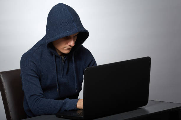 istock Hooded hacker at his laptop 1125974063