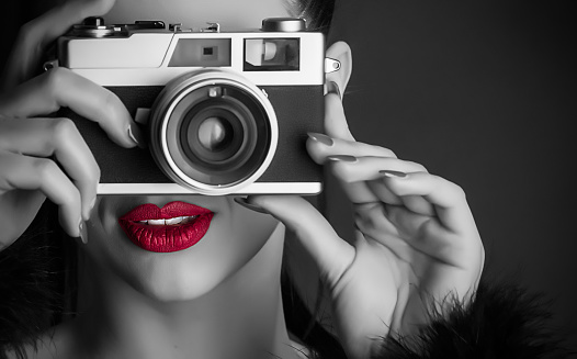 A beautiful girl with a retro camera, a black and white photo with red lips