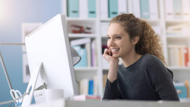 istock Young smiling beautiful woman using a computer in the office and connecting online, she is studying and working 1125982195