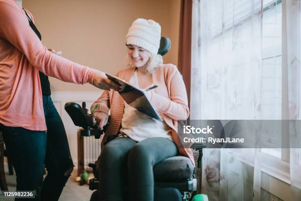Fröhliche Junge Frau Im Rollstuhl Unterzeichnung Zu Hause Papiere Stockfoto und mehr Bilder von Rollstuhl