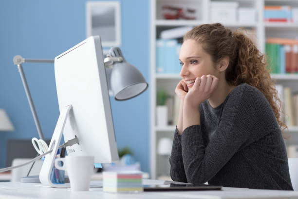 istock Young smiling beautiful woman using a computer in the office and connecting online, she is watching videos and films 1125983050