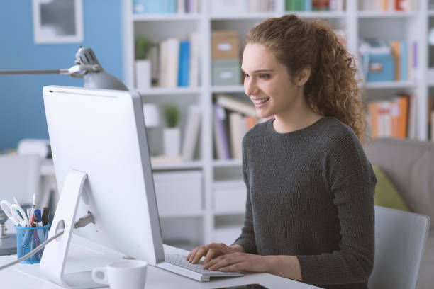 istock Young smiling beautiful woman using a computer in the office and connecting online, she is typing and chatting 1125983382