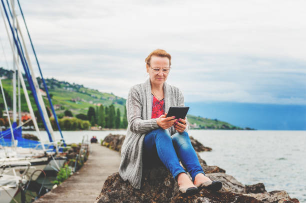 istock Middle age woman resting by the lake, using tablet pc outdoors 1125988620