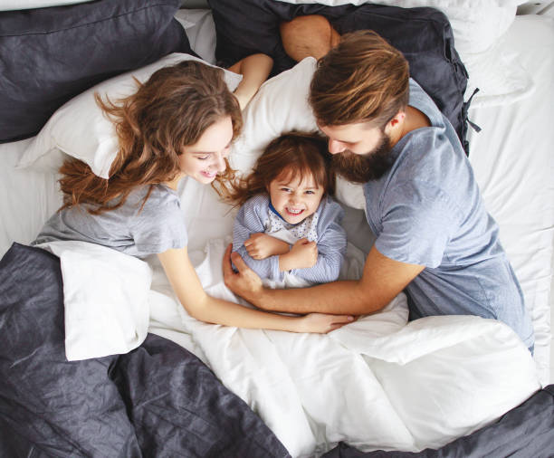 幸せな家族の母、父と子のベッドで - pillow child play family ストックフォトと画像