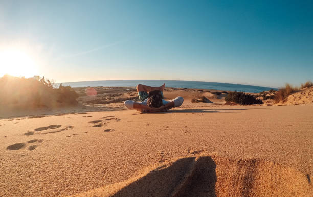 istock Man resting on sand at sunset 1125991035