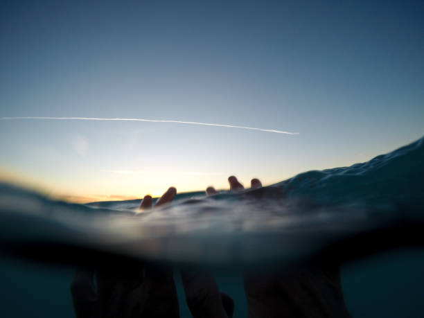 istock Hands under the sea surface at sunset 1125992557