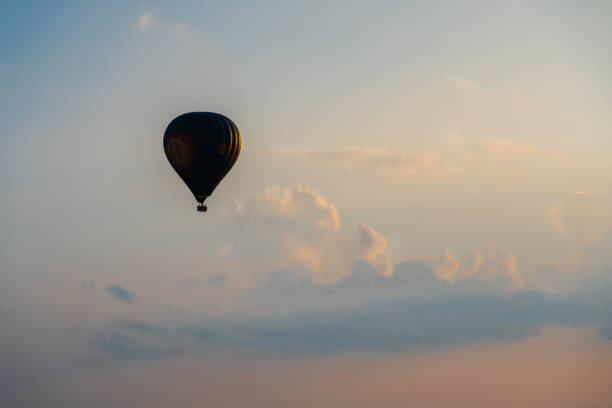 Hot air balloon flying in front of clouds in the sunset