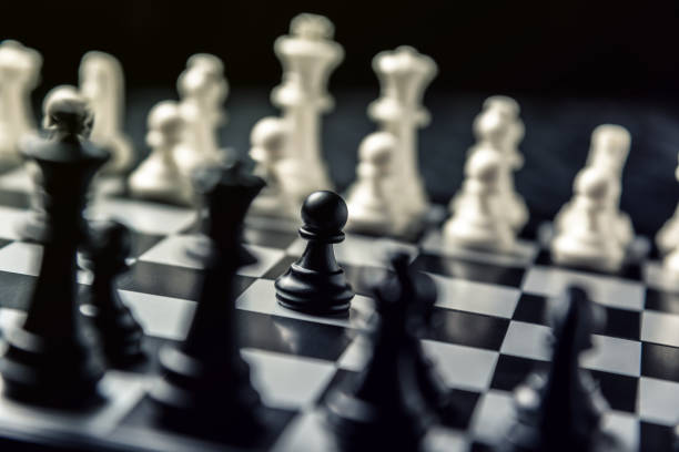 istock Chess board with black and white chess facing each other. Black pawn is going to attack 1125998175