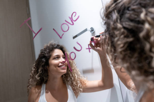 Woman in the bathroom writing a message on the mirror with a lipstick Portrait of a beautiful Latin American woman in the bathroom writing a love message on the mirror with a lipstick mirror writing stock pictures, royalty-free photos & images