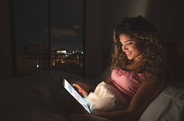 istock Young woman at home watching videos in bed on her tablet computer 1125999612