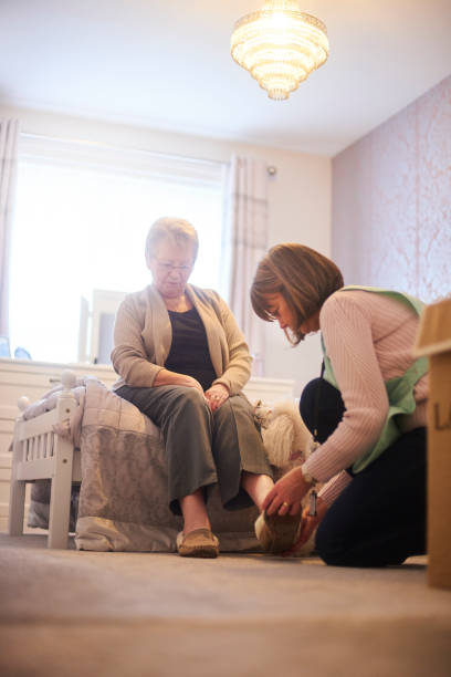 istock Home carer putting senior womans slippers on 1126004893