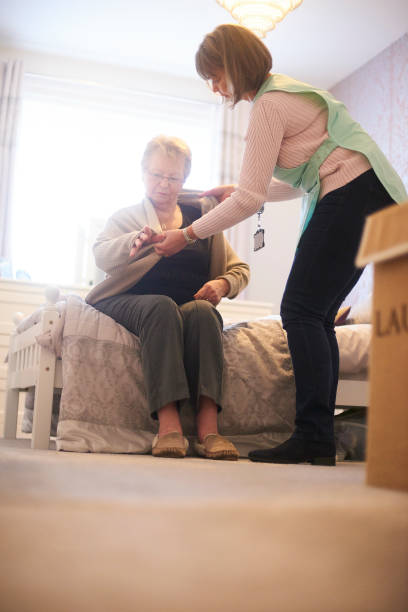 istock Senior woman assisted by home carer getting dressed 1126004957
