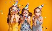 happy birthday children girls with confetti on yellow background