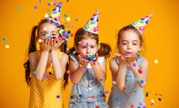 happy birthday children girls with confetti on yellow background happy birthday children girls with confetti on  colored yellow background twin photos stock pictures, royalty-free photos & images