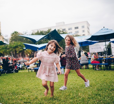 Adorable little girls in a vintage pink smocked dress and flowered jumper, run around. Nostalgic, retro styled image. Peace, love, and childhood. Full of energy, vitality and a cool festival feeling