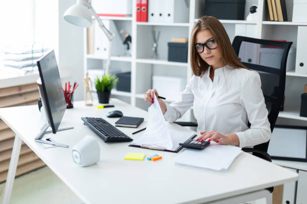 istock Young girl sitting at the table and working with a computer, documents and calculator 1126010275