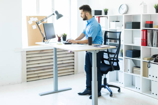 istock A young man standing in the office and working at the computer table. 1126010276