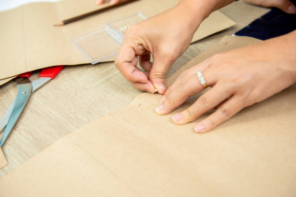 istock Hands of woman designer pinning paper pattern on fabric 1126011097