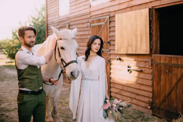 boho style newlyweds standing near horse