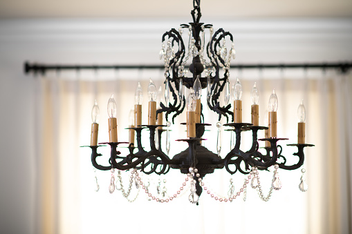 Electrical Candlestick chandelier with crystals hangs from the ceiling of a dining room.