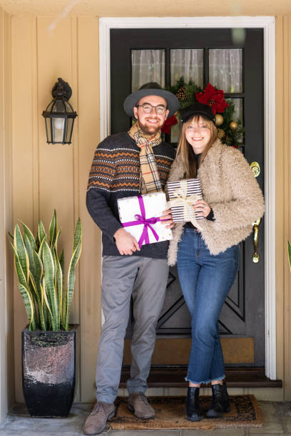 istock Woman Offers Gift at the Front Door 1126015314