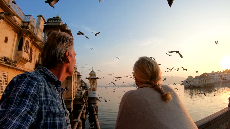 Couple pause above lake and floating palace at sunrise