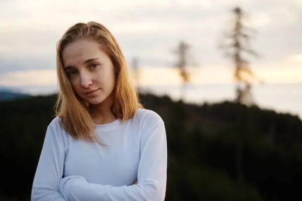 A young teenage girl with acne on a hilltop in the Oregon wilderness