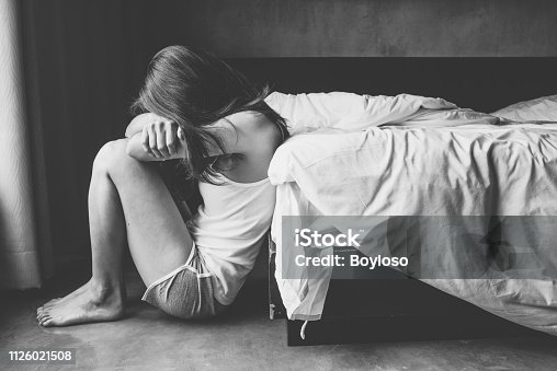 istock Portrait of depressed woman sitting alone on the floor in the bedroom. 1126021508