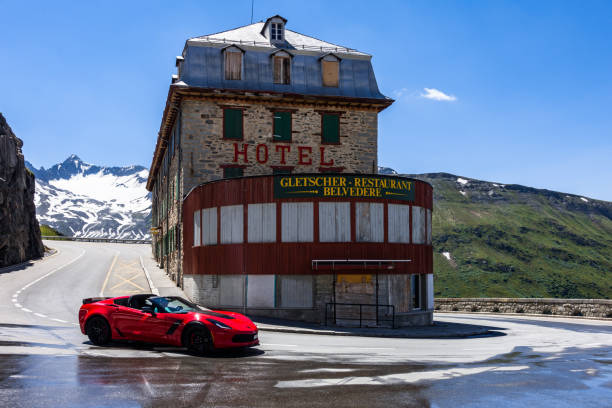 A red sportcar near Hotel Belvedere on the road of Furka Pass, one of the most spectacular alpine road, Valais, Switzerland A red sportcar near Hotel Belvedere on the road of Furka Pass, one of the most spectacular alpine road. Valais, Switzerland, July 2018 furka pass photos stock pictures, royalty-free photos & images