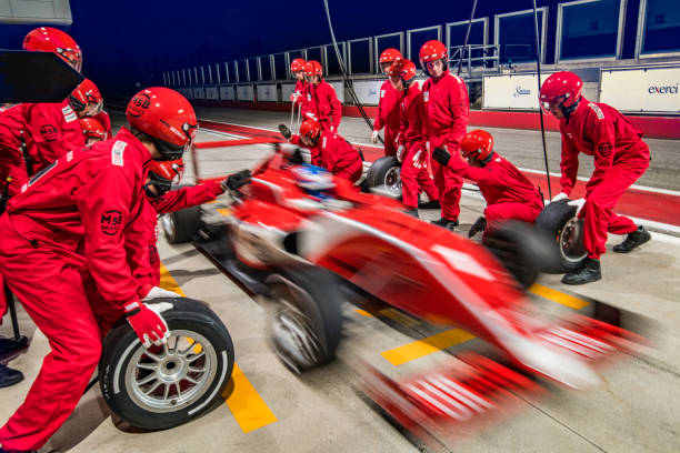 Red formula race car leaving the pit stop Blurred race car leaving the pit after the crew changed it's tires and serviced it. motor racing track photos stock pictures, royalty-free photos & images