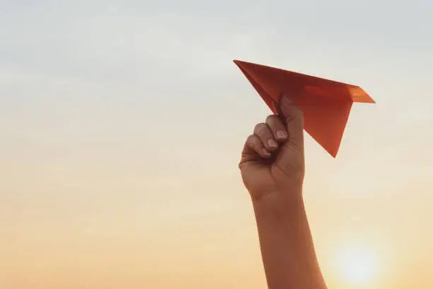 Photo of Woman Hand holding red paper rocket with blue sky background. freedom concept.