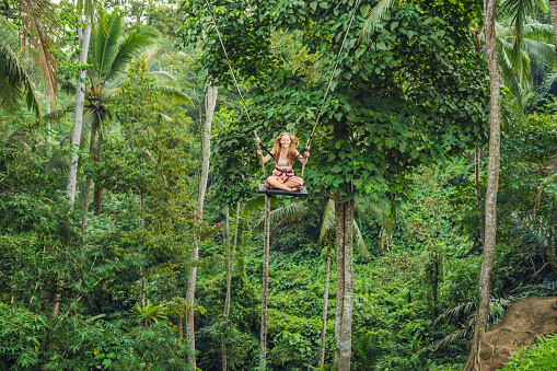 Mujer joven turista en el columpio en la selva de la selva de una isla tropical de Bali photo