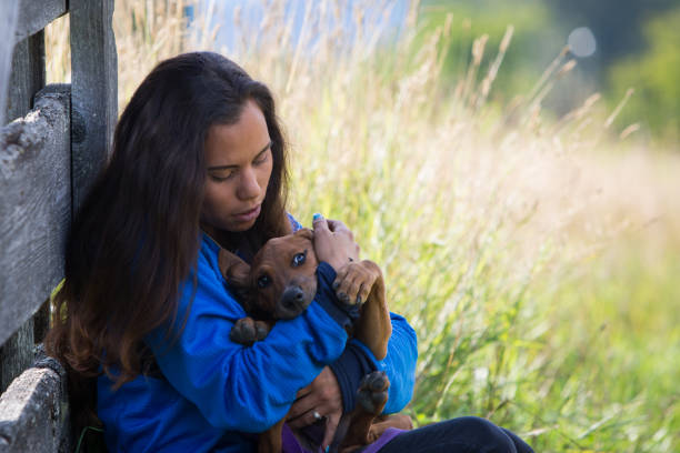 A young indigenous Canadian woman plays with her dog on their agricultural farm