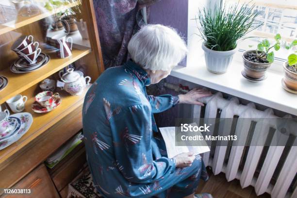 Woman Holding Cash In Front Of Heating Radiator Payment For Heating In Winter Selective Focus Stock Photo - Download Image Now