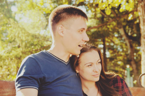istock loving couple sitting on bench thougthfully looking in one direction 1126038597