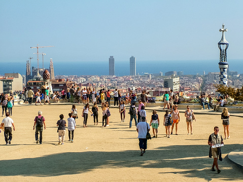 Barcelona, Catalonia, Spain - September 28, 2015: In the Park Guell in sunny weather. View of the Sagrada Familia and the skyscrapers of the Olympic Village. Numerous tourists