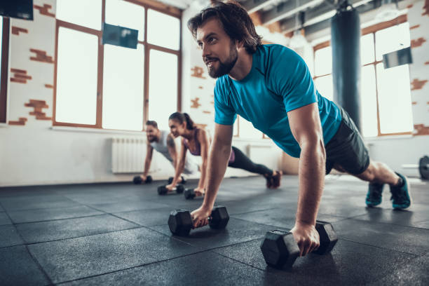 istock Two Men And Woman Doing Push Ups On Dumbbells. 1126048688