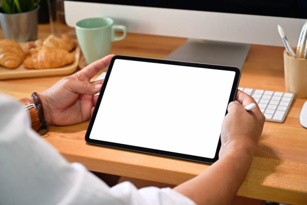 istock Man hand holding blank screen tablet on desk in office 1126048885