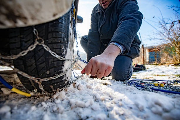 Adult Man Positioning Tire Chains on Car Adult Man Positioning Tire Chains on Car. slippery unrecognizable person safety outdoors stock pictures, royalty-free photos & images