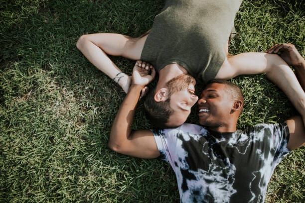 coppia gay rilassante nell'erba - homosexual homosexual couple black ethnic foto e immagini stock