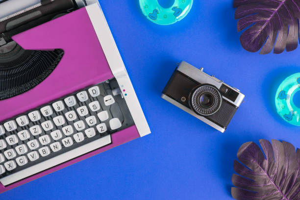 istock Flat lay of typewriter with retro camera and inflatable floats with monstera leaves abstract on blue. 1126058294