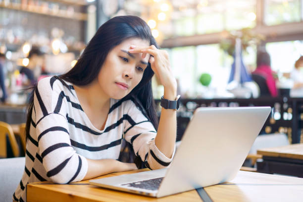 istock Serious and Frustrated asian woman thinking of problem to working a difficult assignment in a desktop, using laptop computer sitting alone at cafe. 1126058338